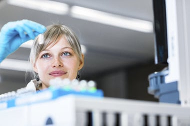 female scientist looking closely at a test tube